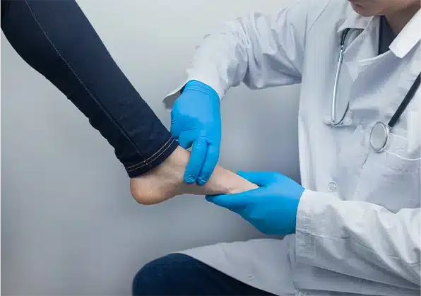 doctor with blue gloves working on a patients bare foot