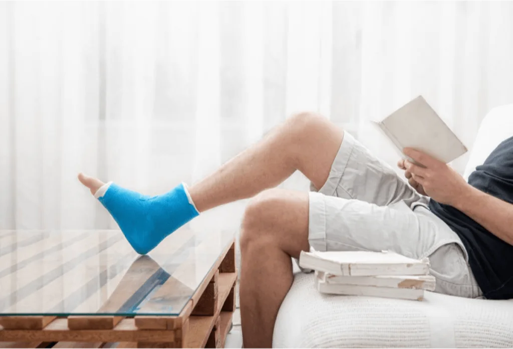 Man sitting with his leg elevated in a cast, recovering from a foot or ankle injury, indicating a need for podiatric care.