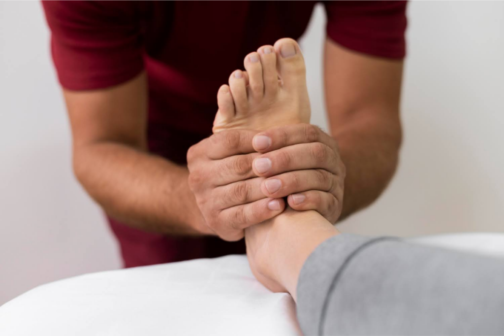 Therapist holding a patient's foot, performing a medical examination or therapy for foot health.