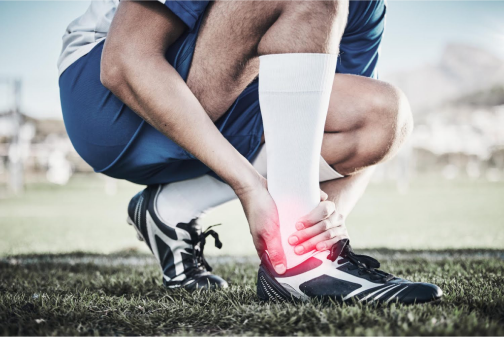 Athlete clutching their ankle in pain on a sports field, highlighting potential injury or foot-related issues.