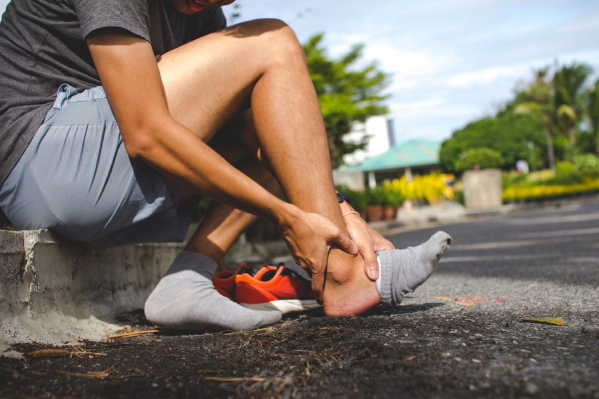 Person sitting on side walk holding his feet