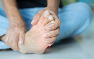 Close-up of a person holding their foot, possibly experiencing pain.
