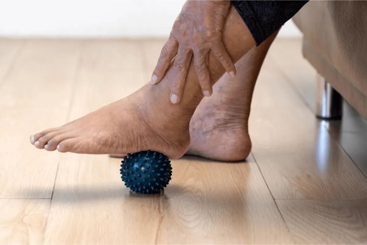 Elderly person massaging his feet over a ball