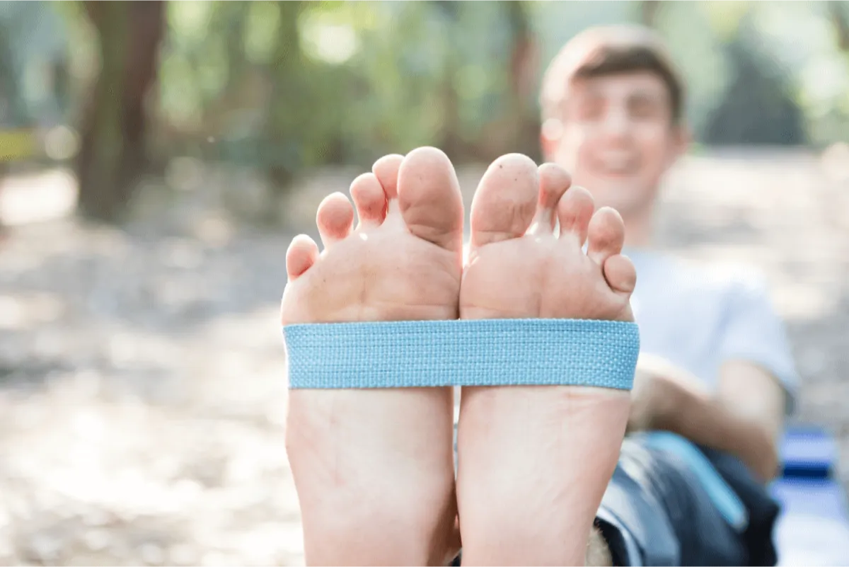 A boy stretching its feet with a elastic belt