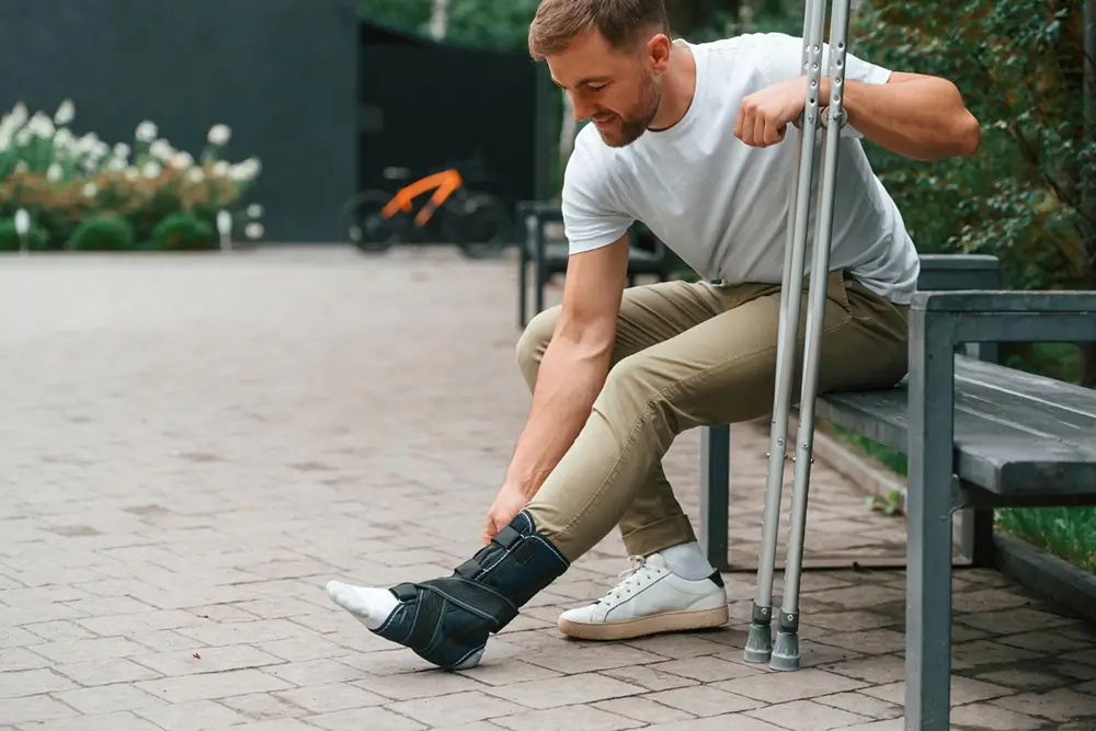 Man wearing an ankle brace with crutches.