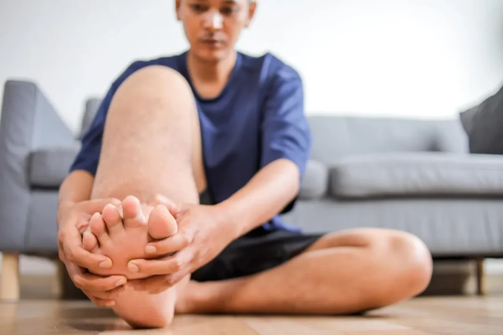 Person holding painful foot indoors