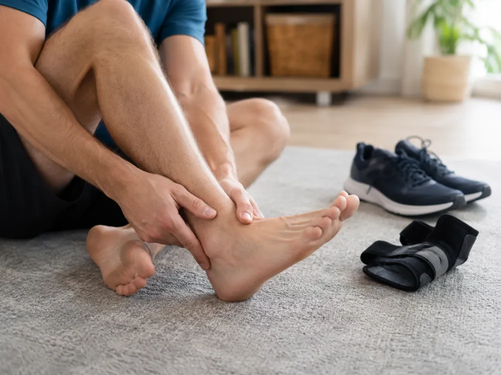 Man checking weak ankle beside brace and shoes